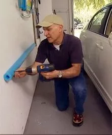 Man attaching a pool noodle to the garage wall